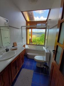 een badkamer met een wastafel, een toilet en een raam bij Le Jardim in Alto Paraíso de Goiás