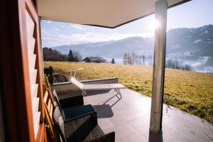 eine Terrasse mit einer Bank, einem Tisch und Stühlen in der Unterkunft Sun & Mountains Cavalese in Cavalese