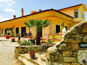 una casa amarilla con una palmera delante de ella en Villa della Mimosa, en Alia
