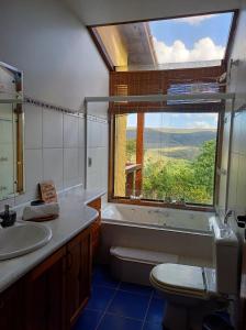 a bathroom with a window and a sink and a toilet at Le Jardim in Alto Paraíso de Goiás
