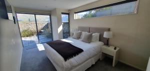 a bedroom with a bed and a large window at Lakeshore Springs Apartments in Wanaka
