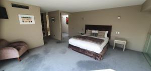 a bedroom with a large bed and a chair at Lakeshore Springs Apartments in Wanaka