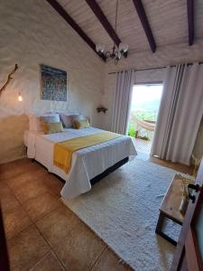 a bedroom with a large bed and a large window at Le Jardim in Alto Paraíso de Goiás