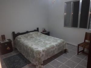 um quarto com uma cama, uma cadeira e uma janela em Alexandre Mayer em Peruíbe