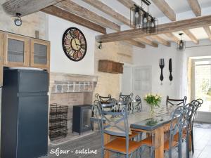 une cuisine avec une table et des chaises et une horloge au mur dans l'établissement Grande maison familiale avec jardin, terrasse et équipements de loisirs, proche forêt de la Charnie - FR-1-410-297, à Chemiré-en-Charnie 25 autres photos