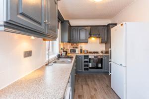a kitchen with gray cabinets and a white refrigerator at Millway Apartments Newcastle Gateshead with Free Parking in Sheriff Hill