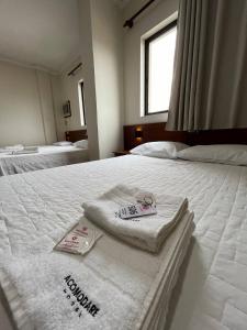 um quarto com duas toalhas numa cama branca em Acomodare Hotel em Tubarão