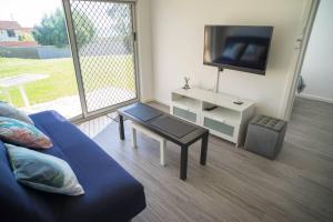 uma sala de estar com um sofá, uma televisão e uma mesa em 6 Sand Sun & Surf 1br 1 Bth em Perth