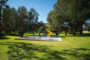 um parque infantil num parque com um escorrega amarelo em 6 Sand Sun & Surf 1br 1 Bth em Perth