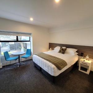 um quarto com uma cama, uma mesa e cadeiras em The Devon Hotel A Heritage Hotel em New Plymouth