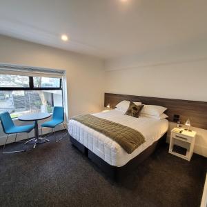 1 dormitorio con 1 cama, mesa y sillas en The Devon Hotel A Heritage Hotel, en New Plymouth