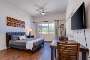 Unit 15 Maui Ohana Modern Studio في Wailuku: غرفة نوم بسرير ومكتب وتلفزيون