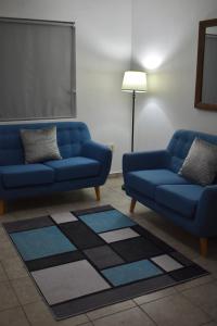 ein Wohnzimmer mit zwei blauen Sofas und einer Lampe in der Unterkunft Gabbys House in private neighborhood in Mexicali