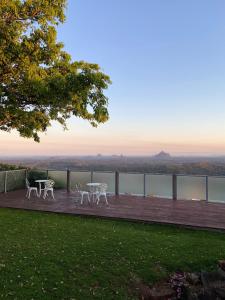 a wooden deck with two tables and a view of the water at Tranquil Park in Maleny