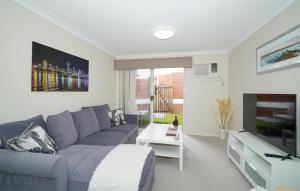 ein Wohnzimmer mit einem blauen Sofa und einem TV in der Unterkunft 6 Light Bright Home In South Perth in Perth