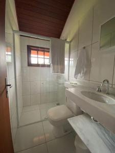 Baño blanco con aseo y lavamanos en Pousada Caminho dos Ventos en Passa Quatro