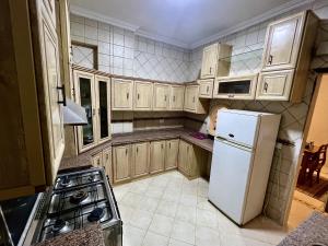 een keuken met houten kasten en een witte koelkast bij NEAR THE PYRAMIDS Inn in Caïro