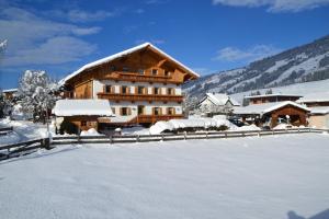 un edificio en la nieve con un patio cubierto de nieve en Biobauernhof Schuster, en Hopfgarten im Brixental