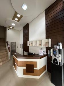 a coffee shop with a counter and a refrigerator at Acomodare Hotel in Tubarão