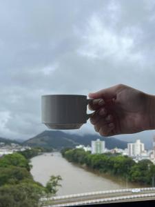 uma pessoa de mão segurando uma luz em frente a um rio em Acomodare Hotel em Tubarão