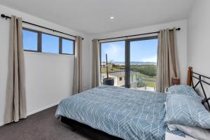 a bedroom with a bed and a large window at Seaglass - Karikari Peninsula Holiday Home in Kaitaia