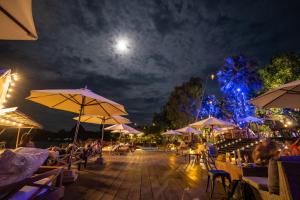 un patio con mesas y sombrillas por la noche en Devi Kampot Resort at Phum Kampot, en Kampot