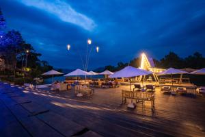 - une terrasse avec des tables, des chaises et des parasols la nuit dans l'établissement Devi Kampot Resort at Phum Kampot, à Kampot