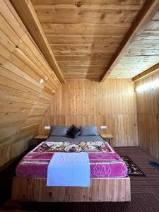 a bedroom with a bed in a wooden room at Pinehill cottage in Jibhi