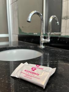 a bag of toothpaste sitting on top of a bathroom sink at Acomodare Hotel in Tubarão