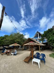 Rincón的住宿－Hostel Beach House，一群人坐在海滩上,拿着椅子和遮阳伞