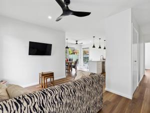 uma sala de estar com um sofá com estampa de zebra e uma ventoinha de tecto em Little Kim Close em Woolgoolga