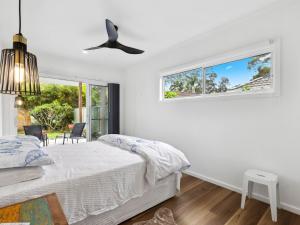 a white bedroom with a bed and a window at Little Kim Close in Woolgoolga