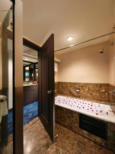 a bathroom with a tub and a large mirror at Mardhiyyah Hotel and Suites in Shah Alam