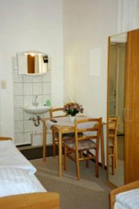 a room with a table and chairs and a sink at Pension Wedding in Berlin