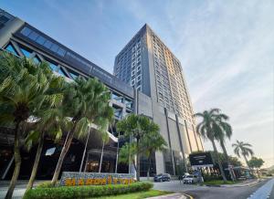 un grand bâtiment avec des palmiers devant lui dans l'établissement Mardhiyyah Hotel and Suites, à Shah Alam