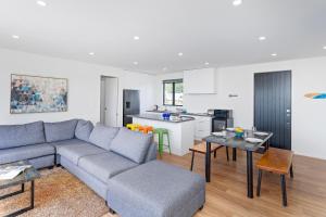 a living room with a couch and a kitchen at Hosts on the Coast - Leighs' Luxury Retreat in Cooks Beach