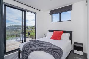 a bedroom with a bed and a large window at Hosts on the Coast - Leighs' Luxury Retreat in Cooks Beach