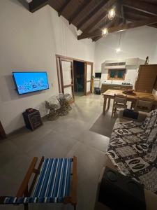 ein Wohnzimmer mit einem Sofa, einem TV und einem Tisch in der Unterkunft Mangue Seco, 120 metros do mar e 100 metros das dunas. in Jaguaruna