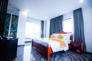 a bedroom with a large bed with yellow pillows at ONE HOTEL in Vĩnh Long