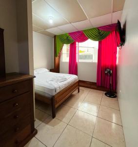 a bedroom with a bed and a window with pink and green curtains at CASA DE HOSPEDAJE PEDERNALES in Pedernales