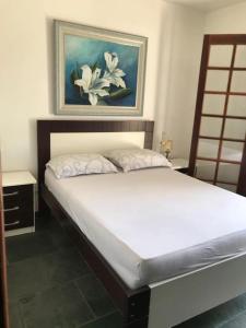 um quarto com uma cama com um quadro na parede em Recanto da Família em Guaratuba
