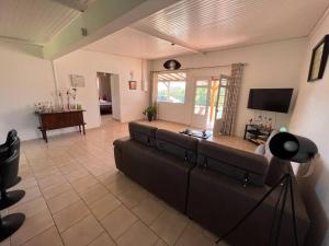 a living room with a couch and a television at 972B-Coin de verdure au pied de la Montagne Pelée in Le Morne Rouge