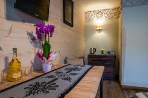 a room with a table with a vase with purple flowers at Pokoje z widokiem na góry i Prywatny Domek z zadaszoną altaną - grillem i ogniskiem. in Zakopane