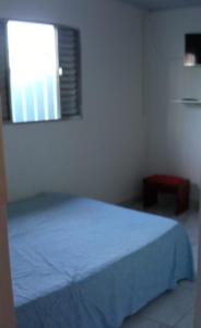 Un dormitorio con una cama azul y una ventana en Casa de Praia com Piscina em Mongagua - Disponivel Carnaval en Mongaguá