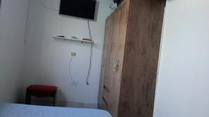 ein Schlafzimmer mit einem Holzschrank mit einem TV an der Wand in der Unterkunft Casa de Praia com Piscina em Mongagua - Disponivel Carnaval in Mongaguá