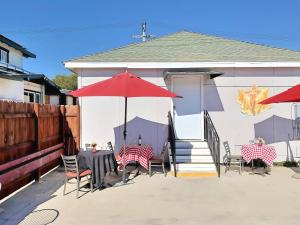 un patio con mesas, sillas y una sombrilla roja en Villa de Las Vegas, en Los Ángeles