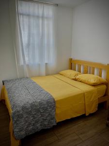 - une chambre avec un lit jaune et une fenêtre dans l'établissement Fluggie, à Ica