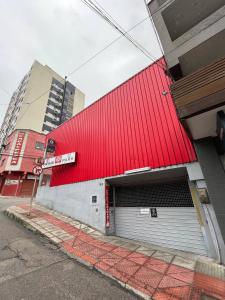 a red building with a garage door on a street at Oscar Palace Hotel - SOB NOVA GESTÃO in Tubarão