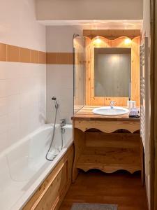 ein Badezimmer mit einer Badewanne, einem Waschbecken und einem Spiegel in der Unterkunft CozyLoge, Orelle & Les 3 vallées in Orelle