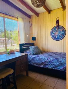 a bedroom with a bed and a desk and a window at Casa El Arrebol, sector Saltos del Laja in Cabrero